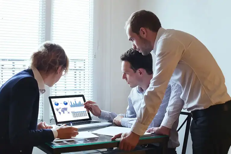 Three analysts look at the charts on a screen