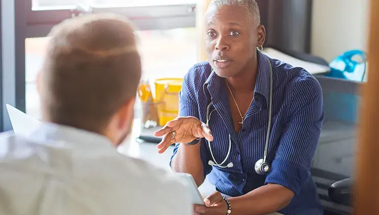 Doctor sat in in their surgery talking with a patient